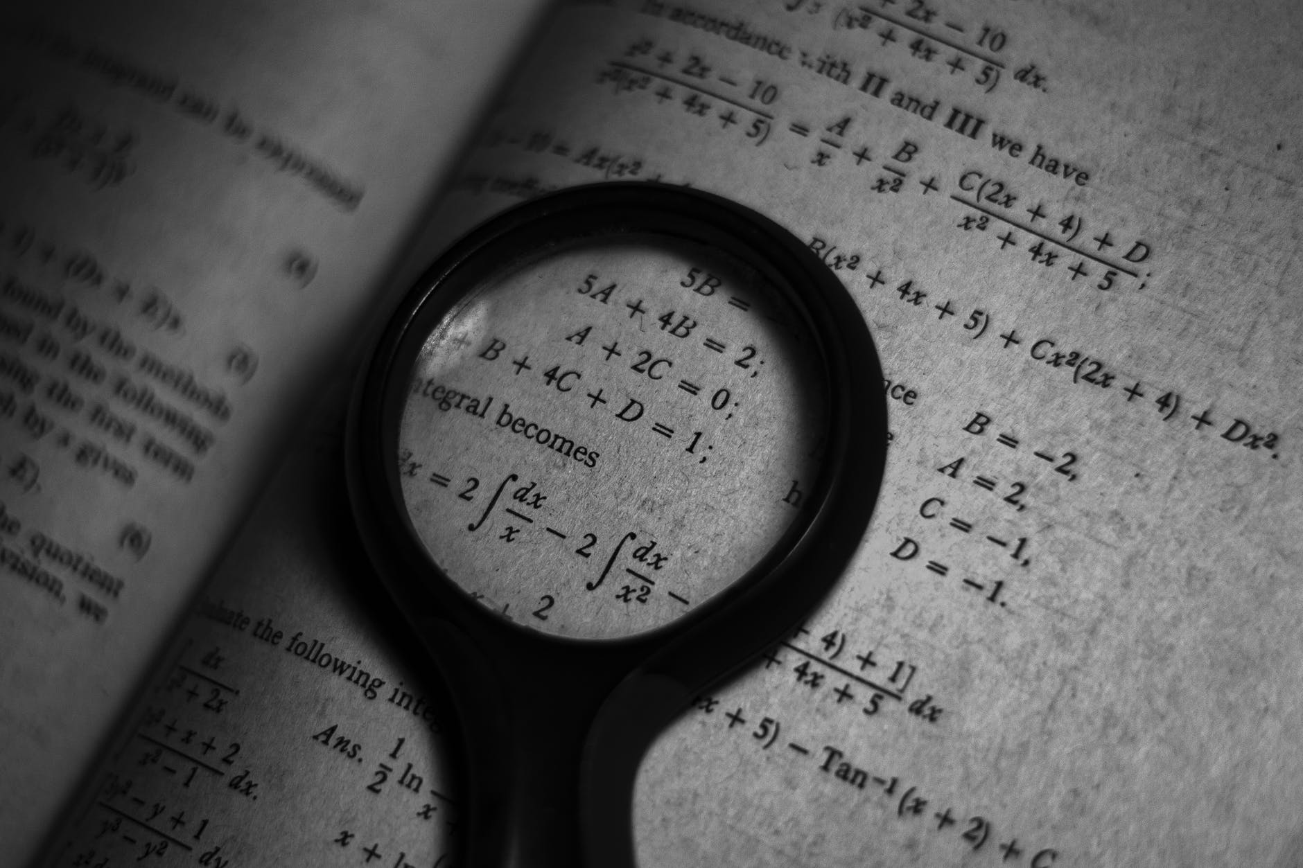 black magnifying glass on a math textbook page with formulas
